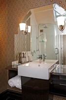 Un baño con un espejo grande, un lavabo blanco y una zona de ducha.