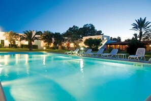 Une piscine avec des chaises longues et un bâtiment en arrière-plan.
