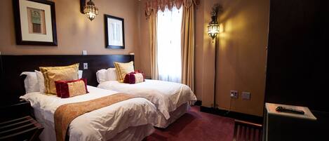 Een hotelkamer met twee bedden, een bureau, een stoel en een televisie.