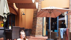 A pool area with a person sitting by the pool, surrounded by outdoor furniture and umbrellas. - Tayfin Royale Hotel & Restaurant (Centurion)