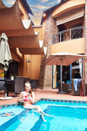 Una piscina al aire libre, sillones reclinables de piscina