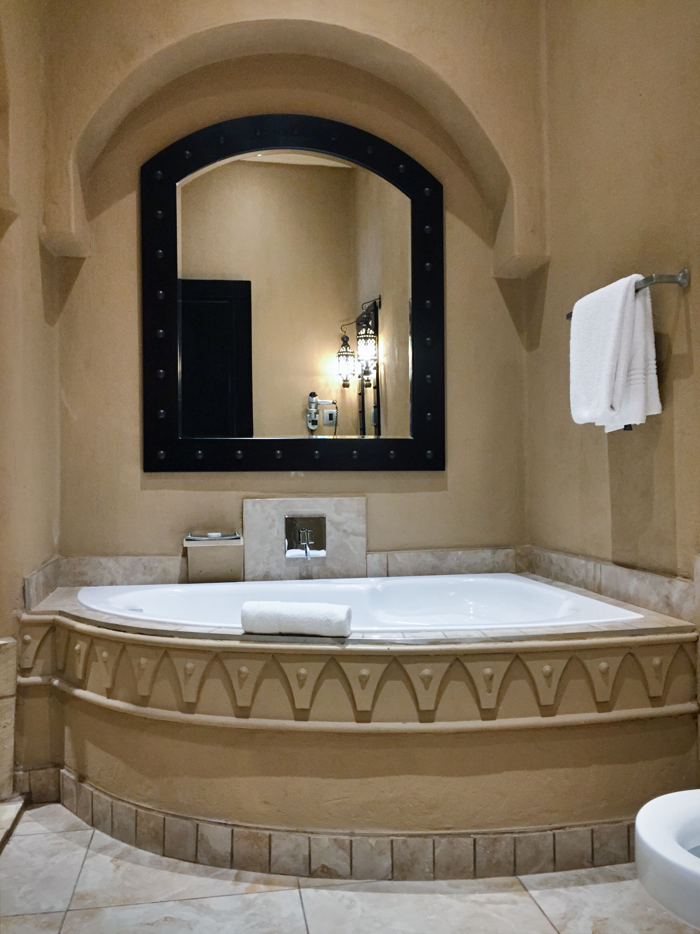 Une salle de bain avec une grande baignoire sur pieds, un miroir avec éclairage intégré et un porte-serviettes.