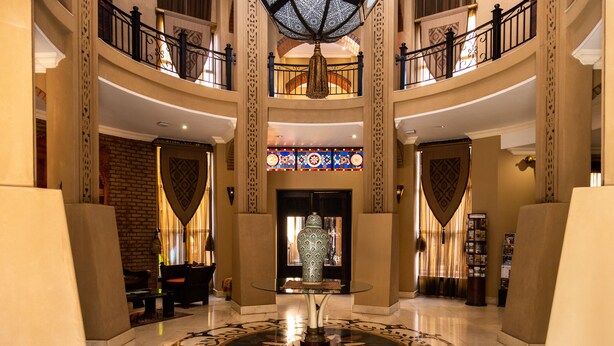 A grand lobby with a central glass table, a large chandelier, and a decorative vase. - Tayfin Royale Hotel & Restaurant (Centurion)