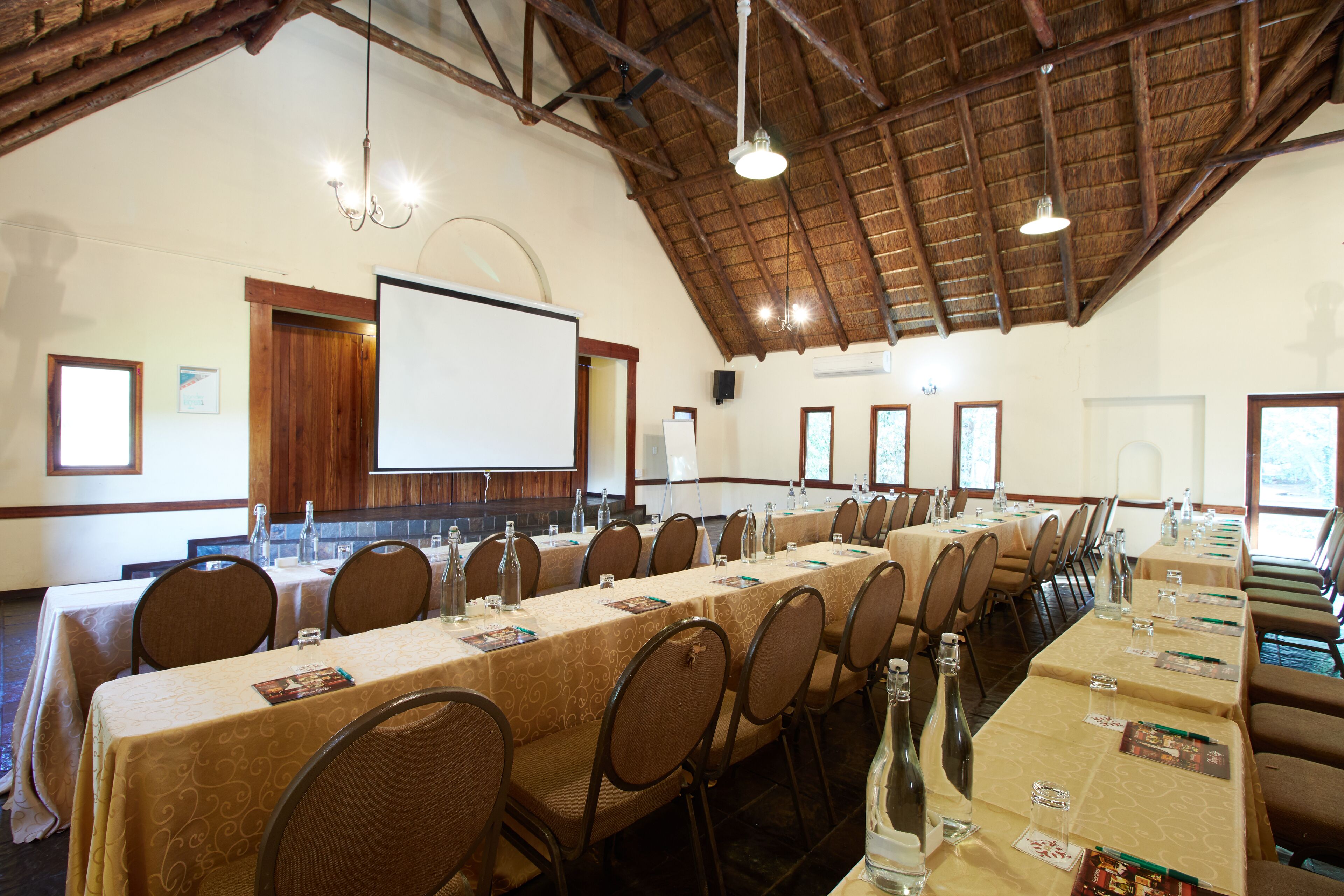 Una sala conferenze con lunghe tavolate, sedie e uno schermo per proiezioni.