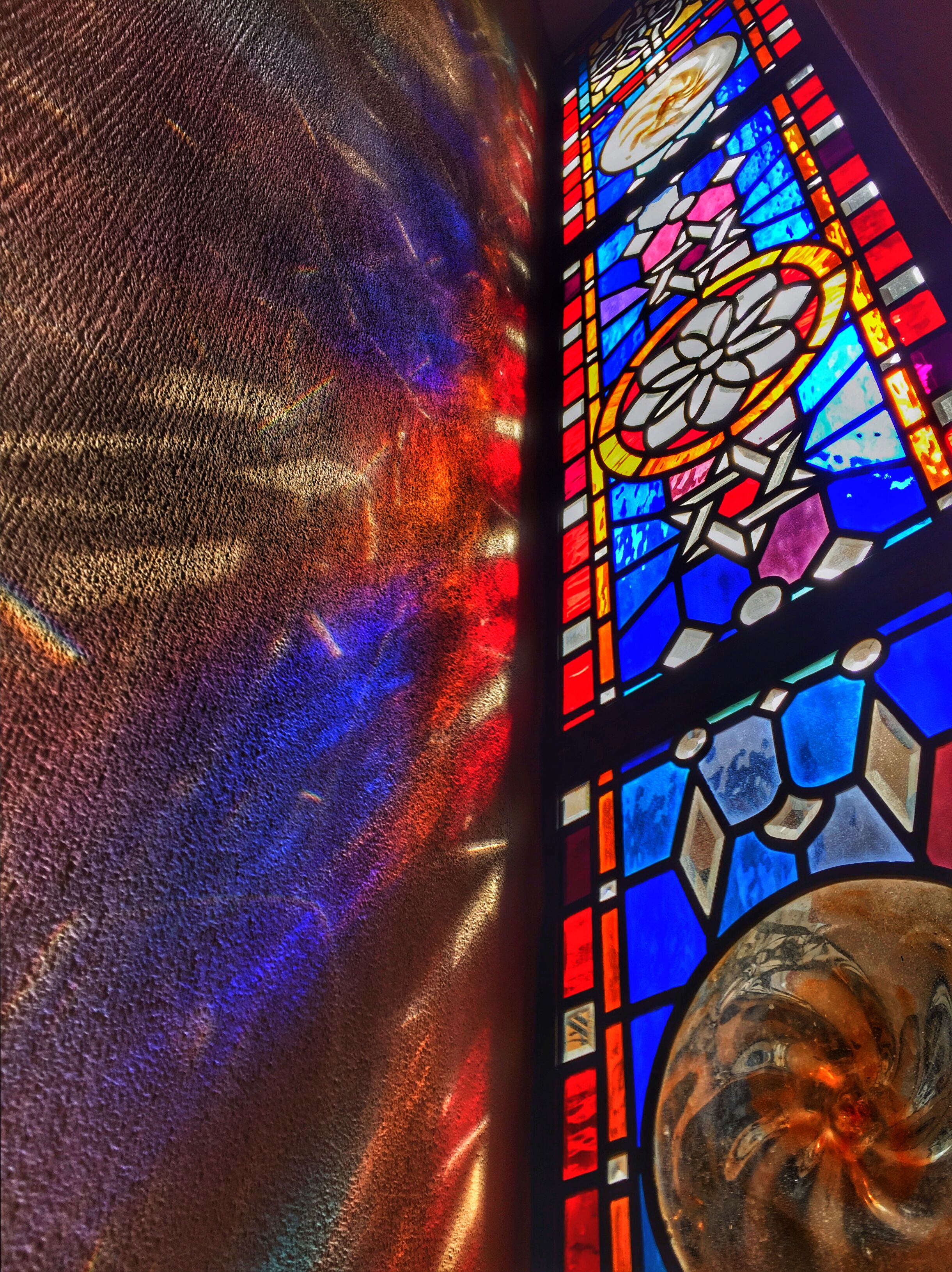 A stained glass window with geometric patterns and a central floral motif.