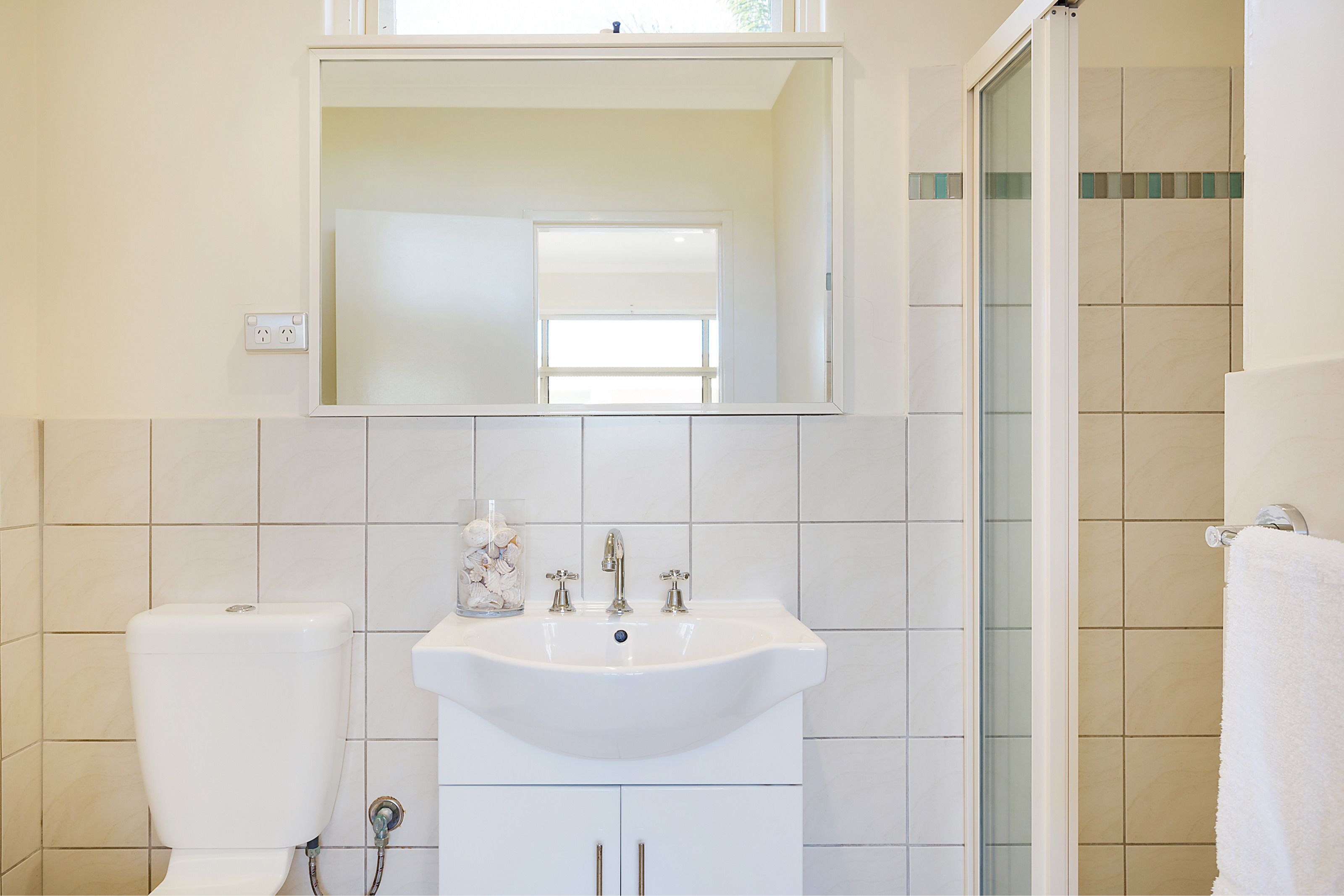 Baño con lavamanos, espejo e inodoro blancos.