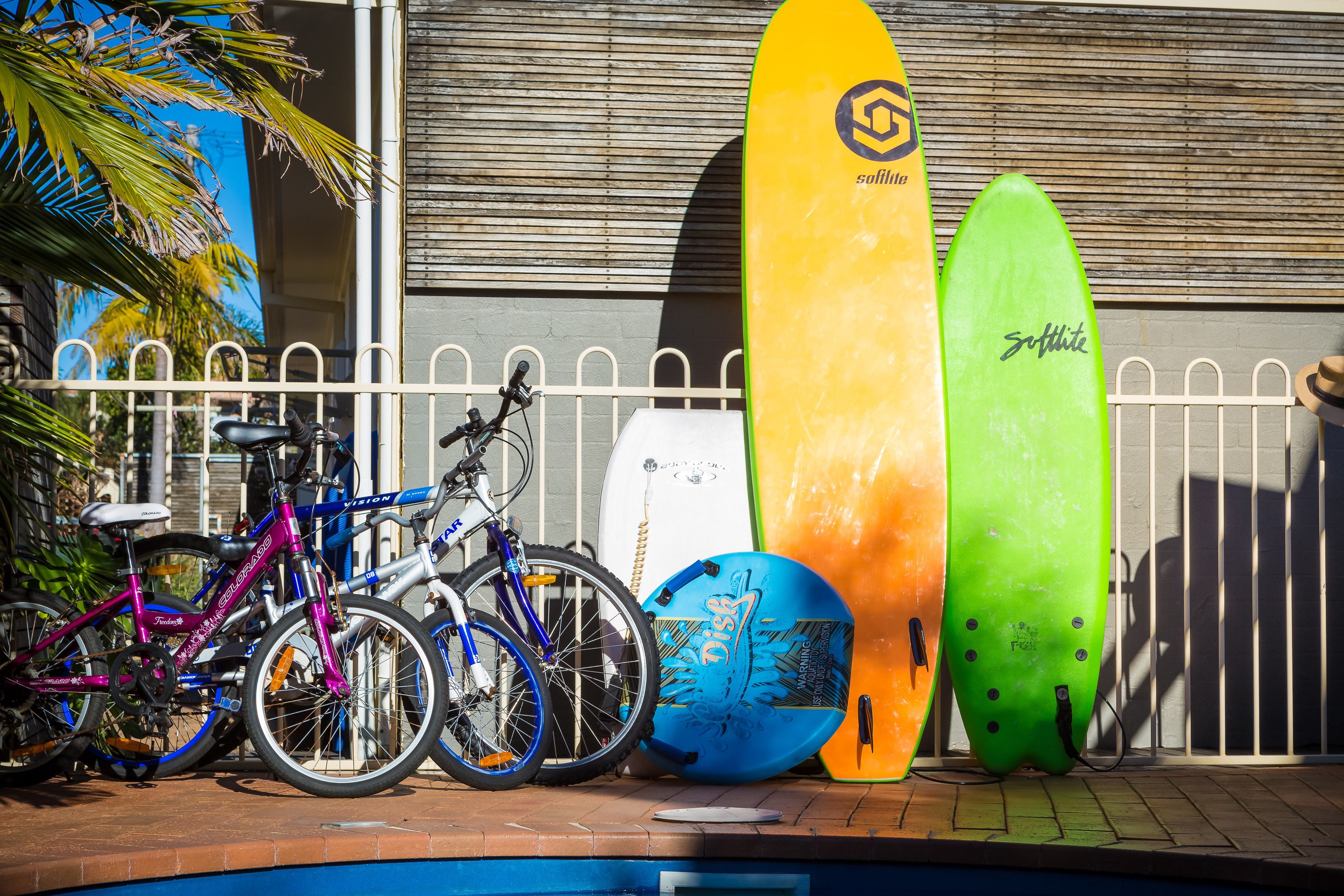 A poolside area with surfboards and bicycles.