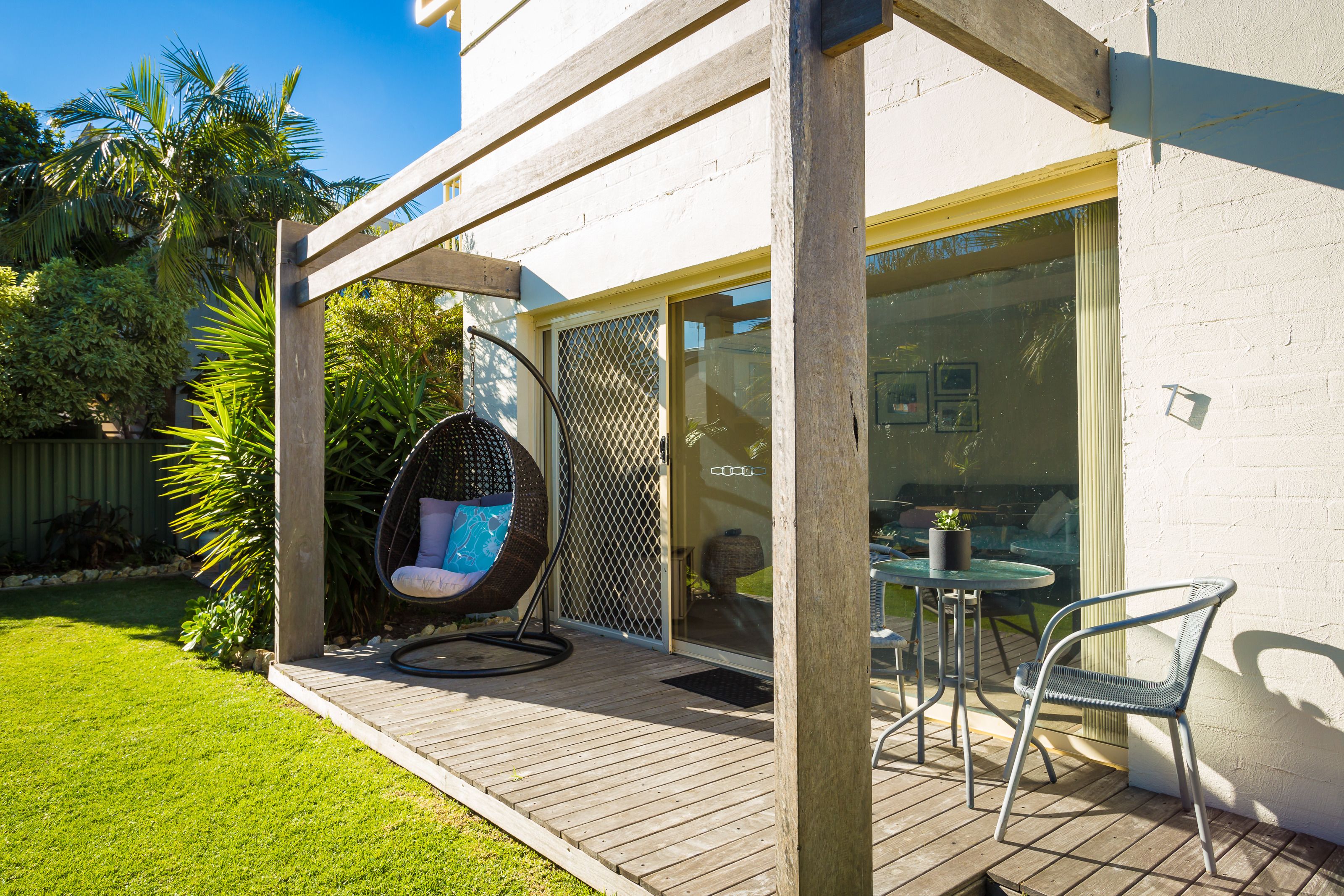 A patio with a hanging chair, a table, and chairs.