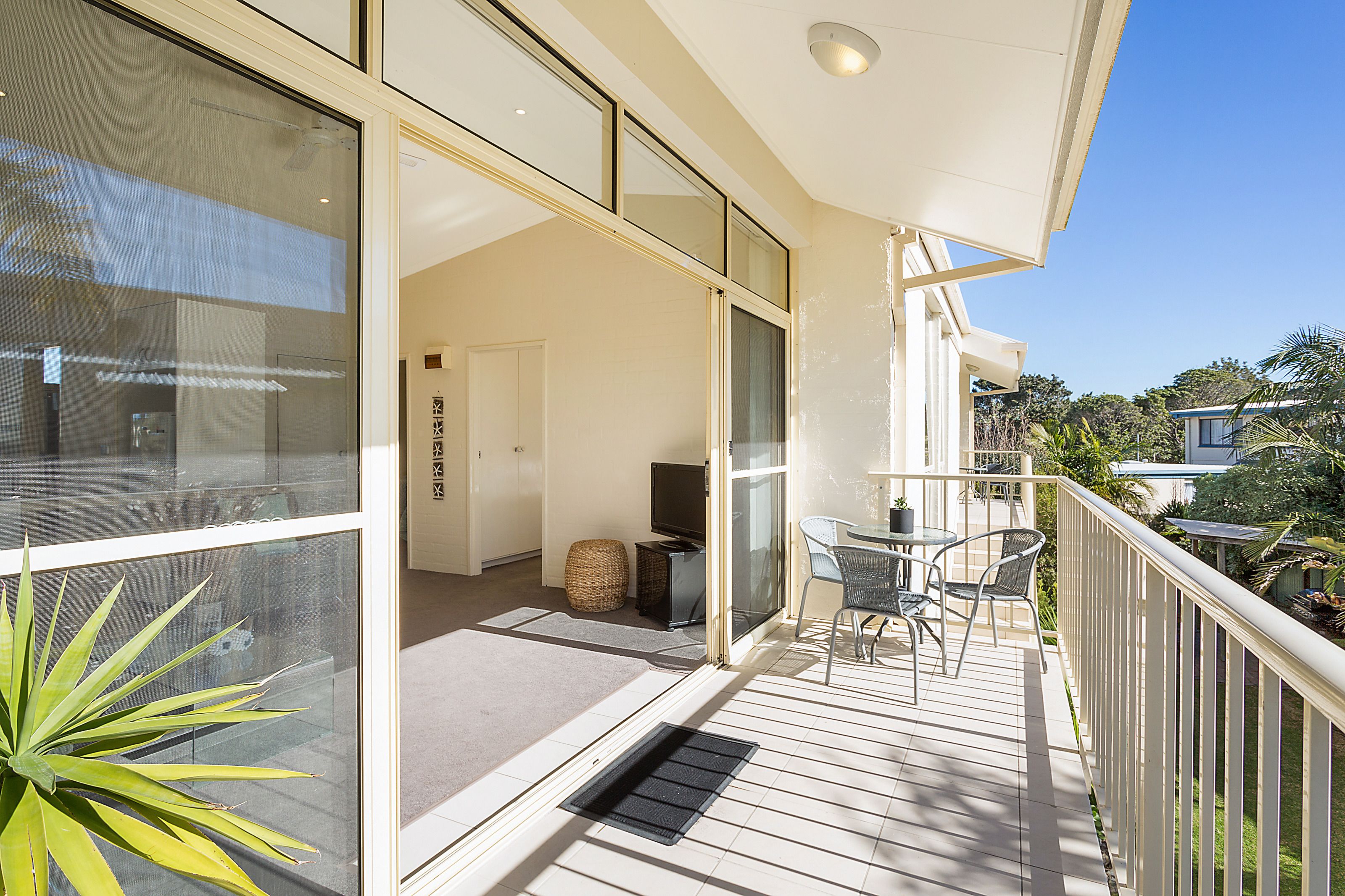 A balcony with a seating area, a television, and a door leading to an interior room.