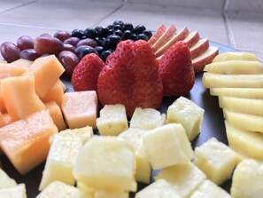 A variety of fresh fruits including strawberries, grapes, blueberries, cantaloupe, and apple slices.