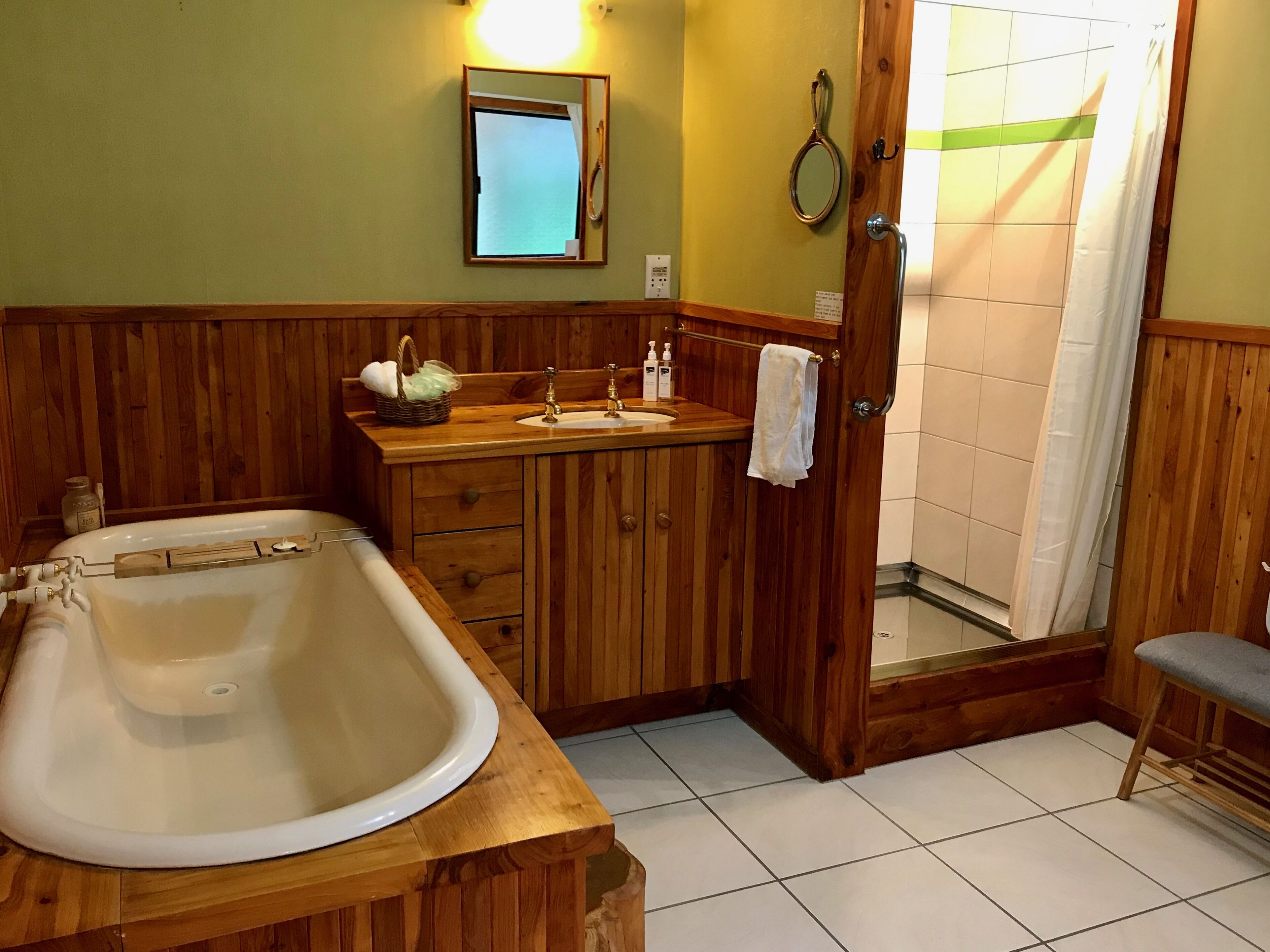 A bathroom with a wooden vanity, a large bathtub, a shower, and a mirror.