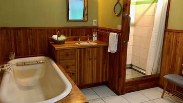 A bathroom with a wooden vanity, a large bathtub, a shower, and a mirror.
