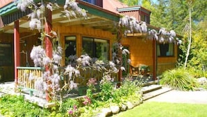 A wooden house with a covered porch and a garden with various plants and flowers. - Murchison Lodge (Murchison)