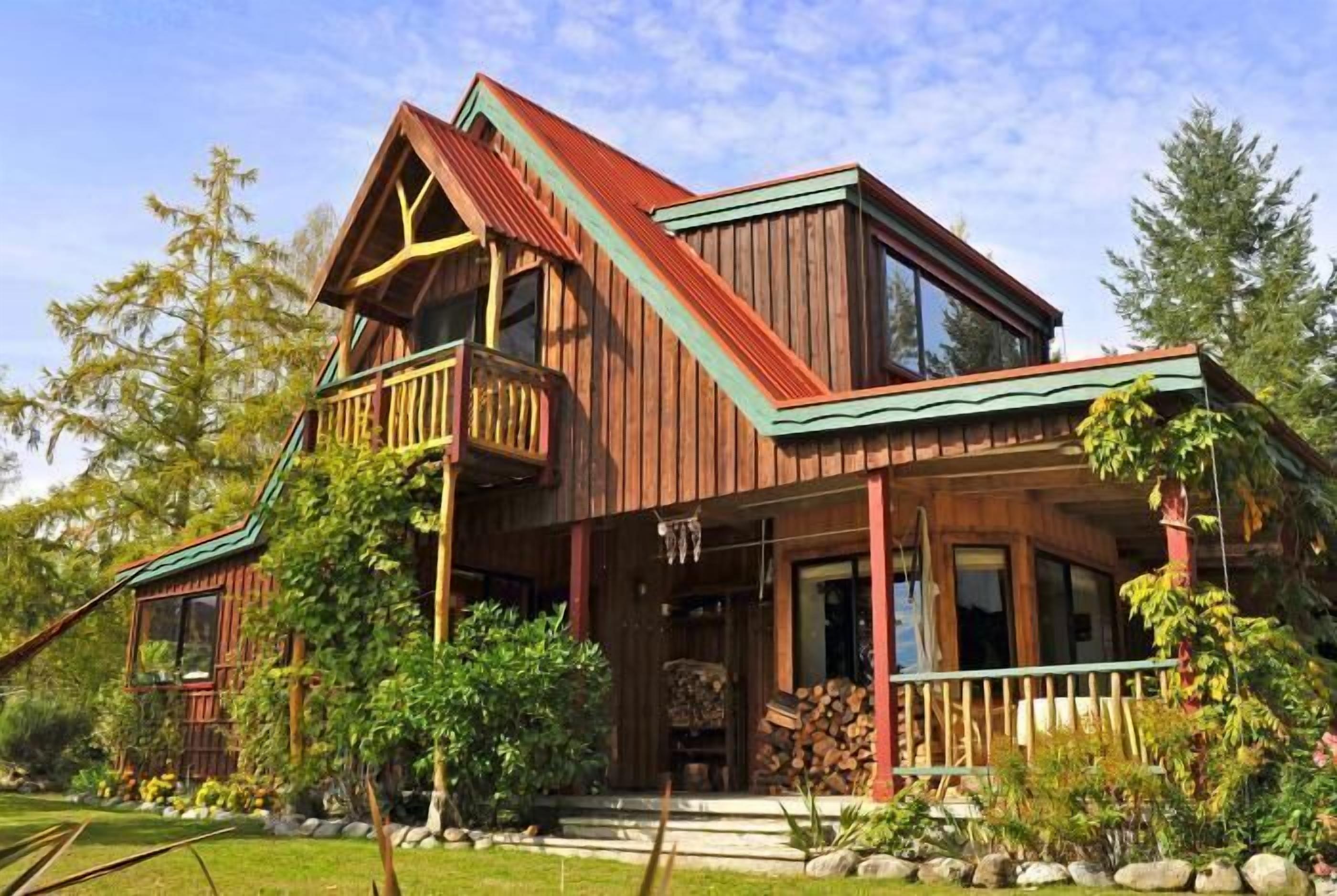 Une cabane en bois dotée d’un balcon, d’une véranda et d’une cheminée en pierre.