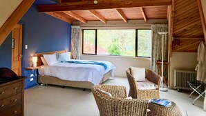 A bedroom with a bed, a dresser, a wicker chair, a standing lamp, and a window with curtains. - Murchison Lodge (Murchison)