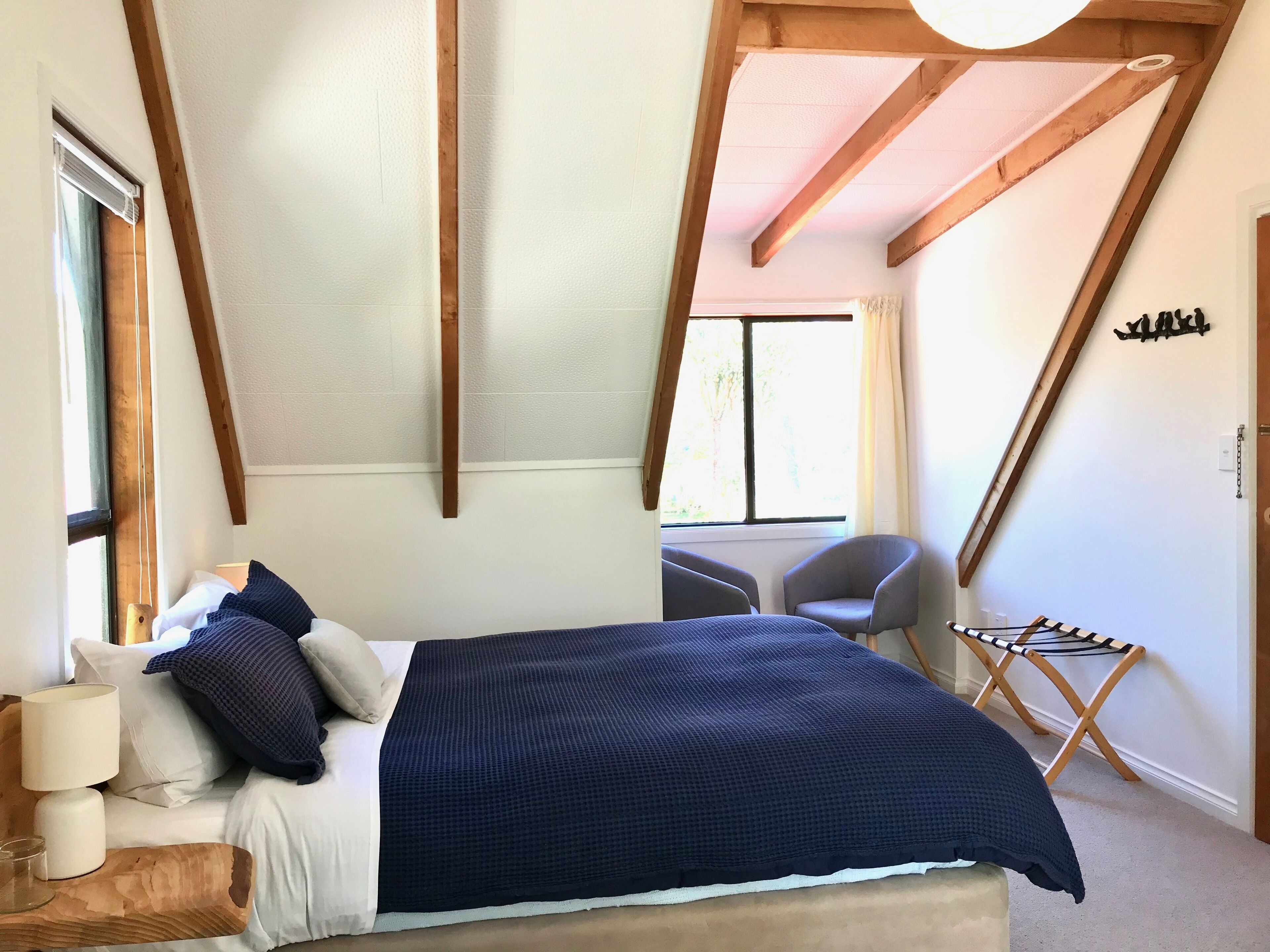 Ein Schlafzimmer mit einem Bett, einem Sessel, einem kleinen Tisch und einem Fenster.