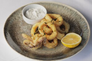 Ein Teller gebratene Calamare mit Zitrone und eine kleine Schüssel Gewürzmischung.