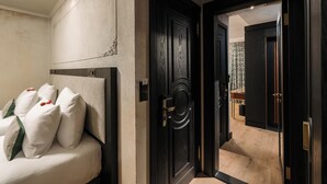 A bedroom with a bed, pillows, a dark wooden door, and a view into another room. - Tria Elegance Istanbul (Istanbul)