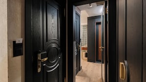 A hallway with dark wooden doors, a light wooden floor, and a patterned wall. - Tria Elegance Istanbul (Istanbul)