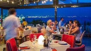 A restaurant with tables set for dining, chairs, and a view of the cityscape at night. - Tria Elegance Istanbul (Istanbul)