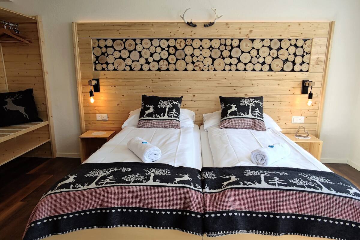 A double bed with two pillows, a headboard with a wooden log pattern, and bedside lamps.