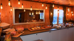 A breakfast buffet setup with bread, pastries, and a fruit bowl. - Gasthaus Alpina (Tschappina)