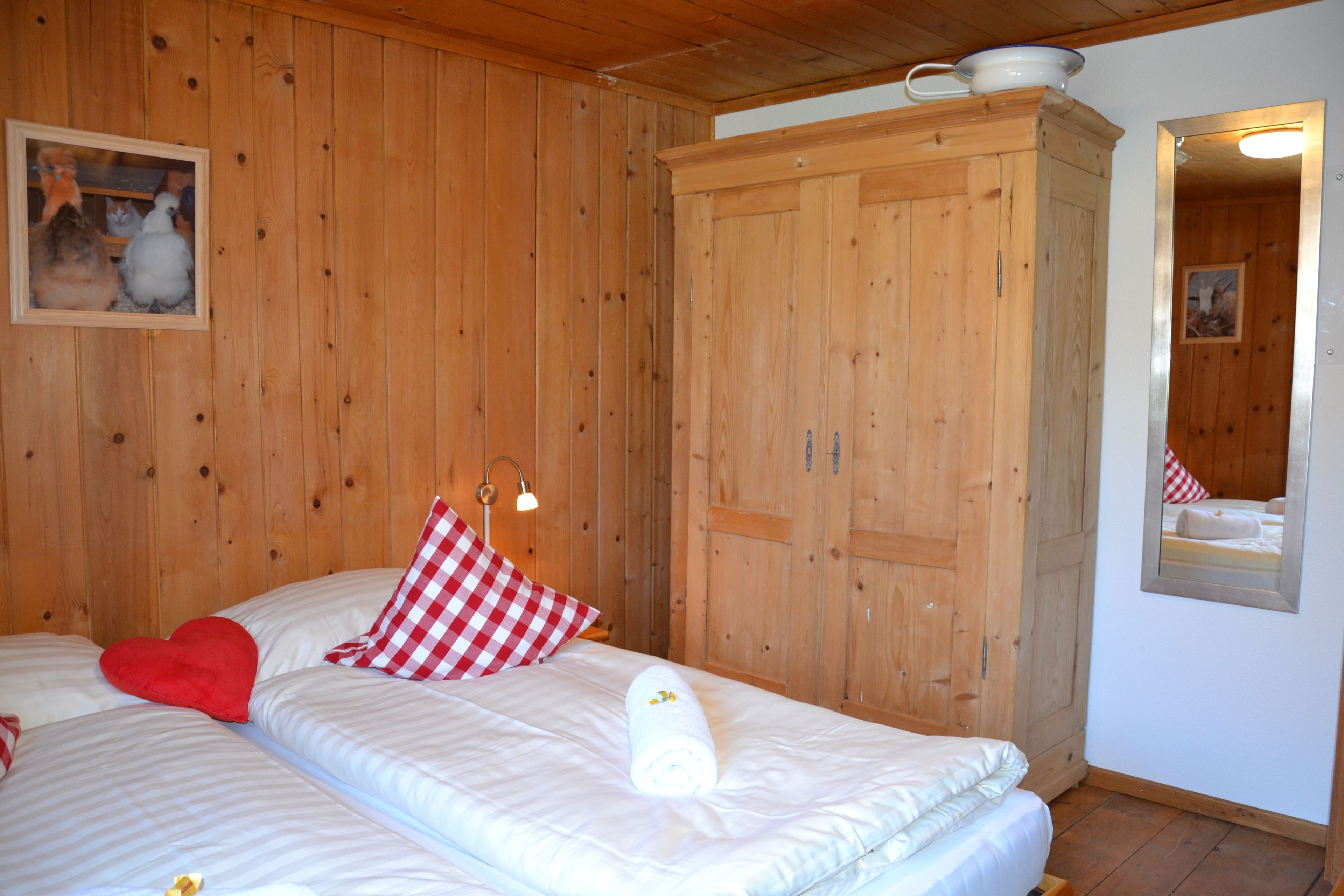 Ein Zimmer mit Holzwänden, einem Bett, einem Kleiderschrank und einem Spiegel.
