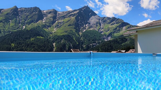 A swimming pool with a mountain view. - Gasthaus Alpina (Tschappina)