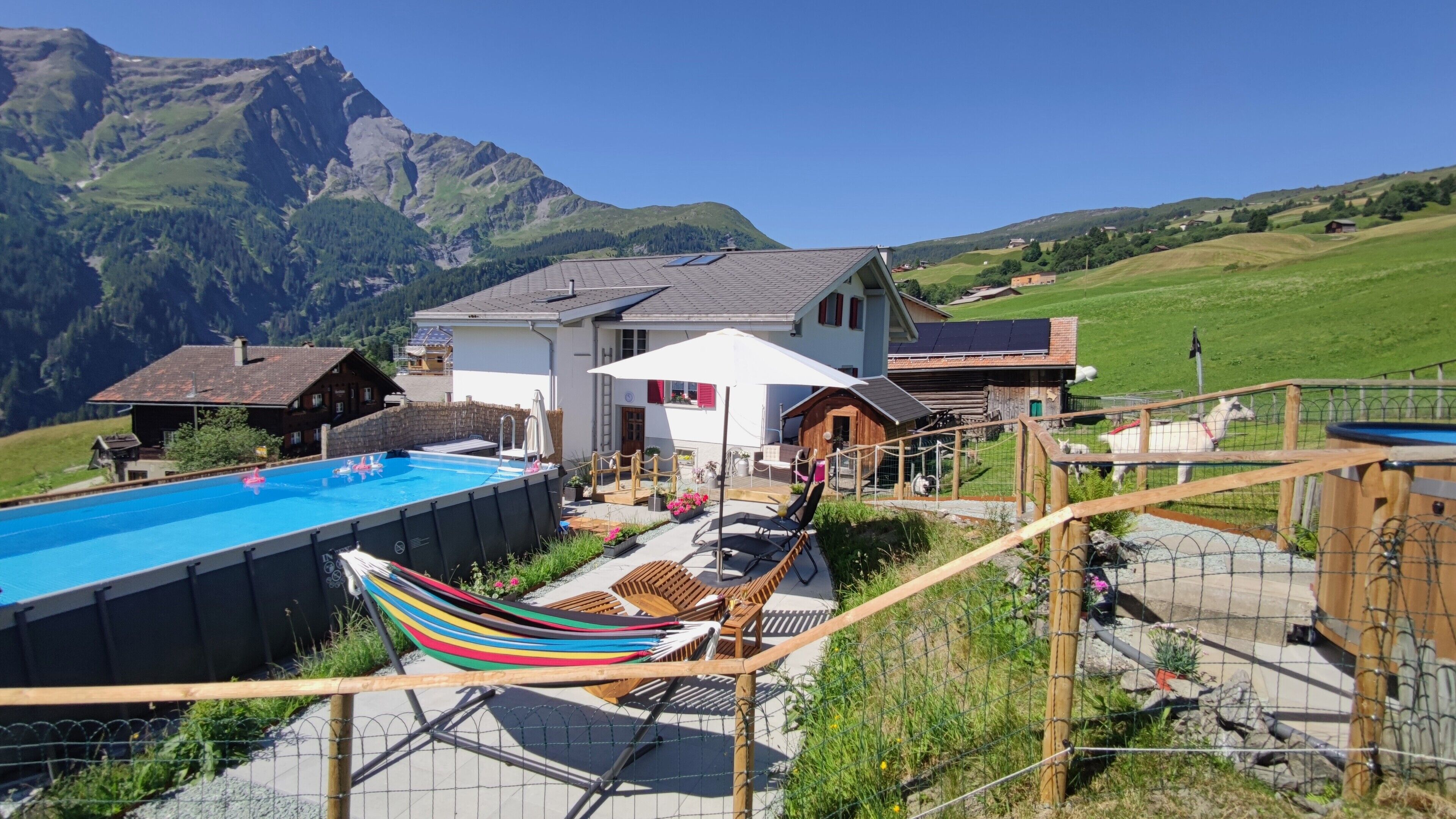 Ein Poolbereich mit Hängematte, Liegestühlen und Bergblick.