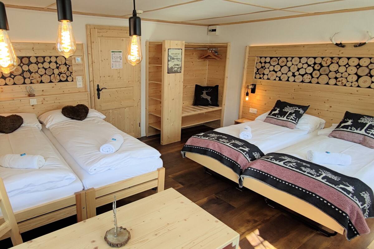 A room with two beds, wooden headboards, and a wooden table.