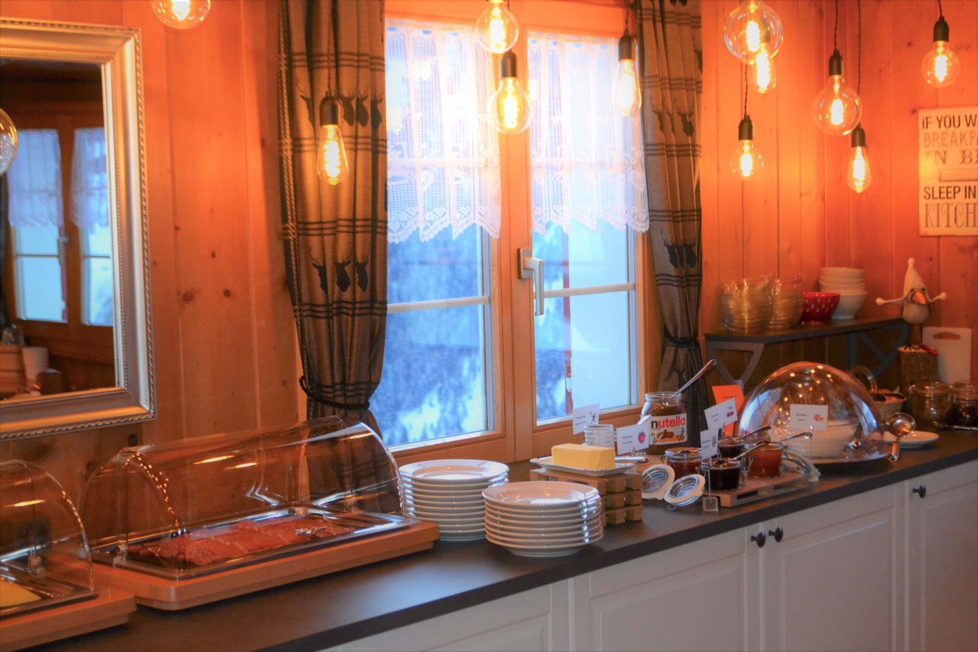 Une cuisine aménagée avec un buffet, comprenant des assiettes, une planche à fromages et divers condiments.