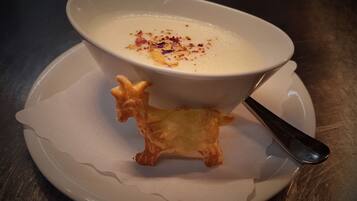 En skål suppe på en hvid tallerken med en ske.