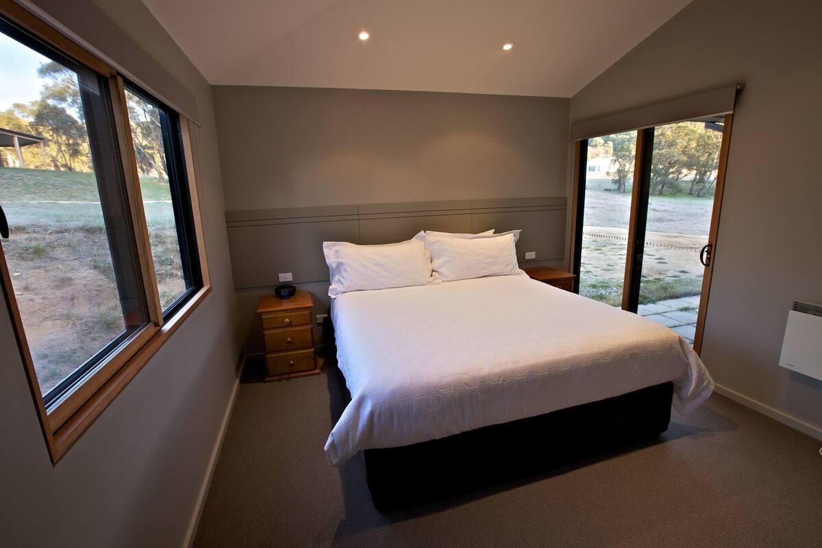 Une chambre moderne avec un grand lit, une table de chevet et une fenêtre.