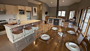A modern kitchen with a central island, bar stools, and a dining table set for six. - Snowy Wilderness (Ingebirah)