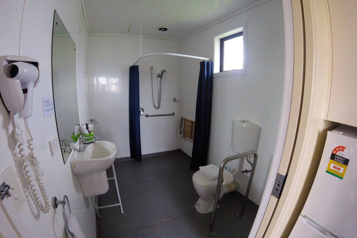 A compact bathroom with a toilet, bidet, and sink. There's a hairdryer on the wall and a window providing natural light.