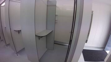Un pasillo con cubículos, cada uno con un estante pequeño y una puerta.