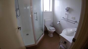 Uma casa de banho com chuveiro em cabine de vidro, sanita e lavatório com porta-toalhas.