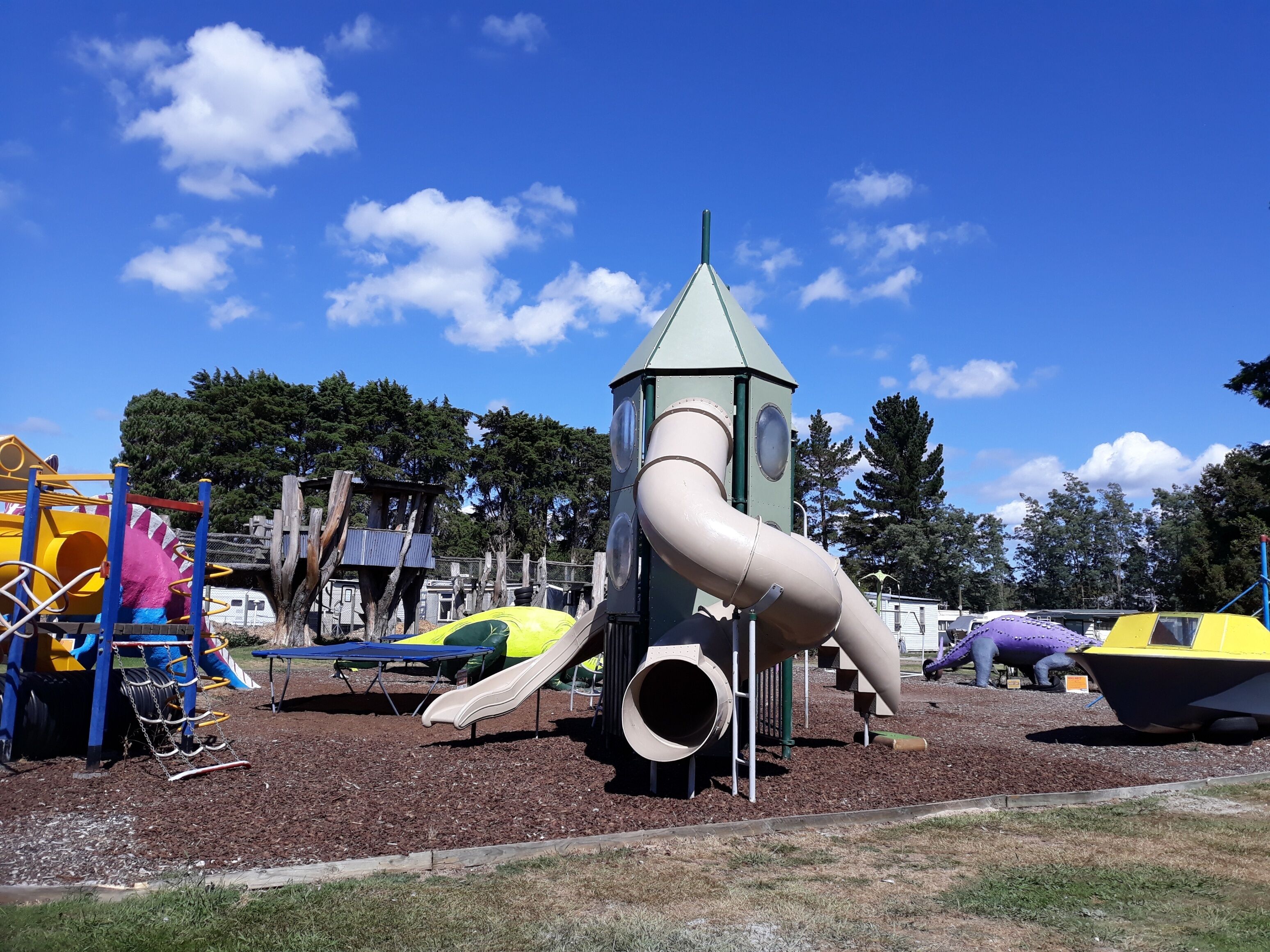 Une aire de jeux avec un toboggan, des structures d’escalade et une petite tour.