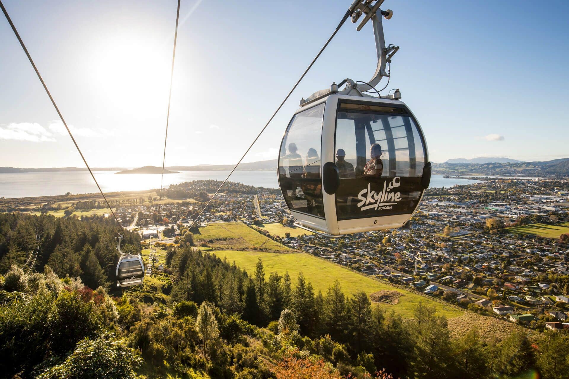 Eine Seilbahn mit Skyline-Logo, die einen Blick auf eine Küstenstadt und ein Gewässer bietet.