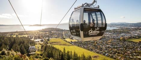 Eine Seilbahn mit Skyline-Logo, die einen Blick auf eine Küstenstadt und ein Gewässer bietet.