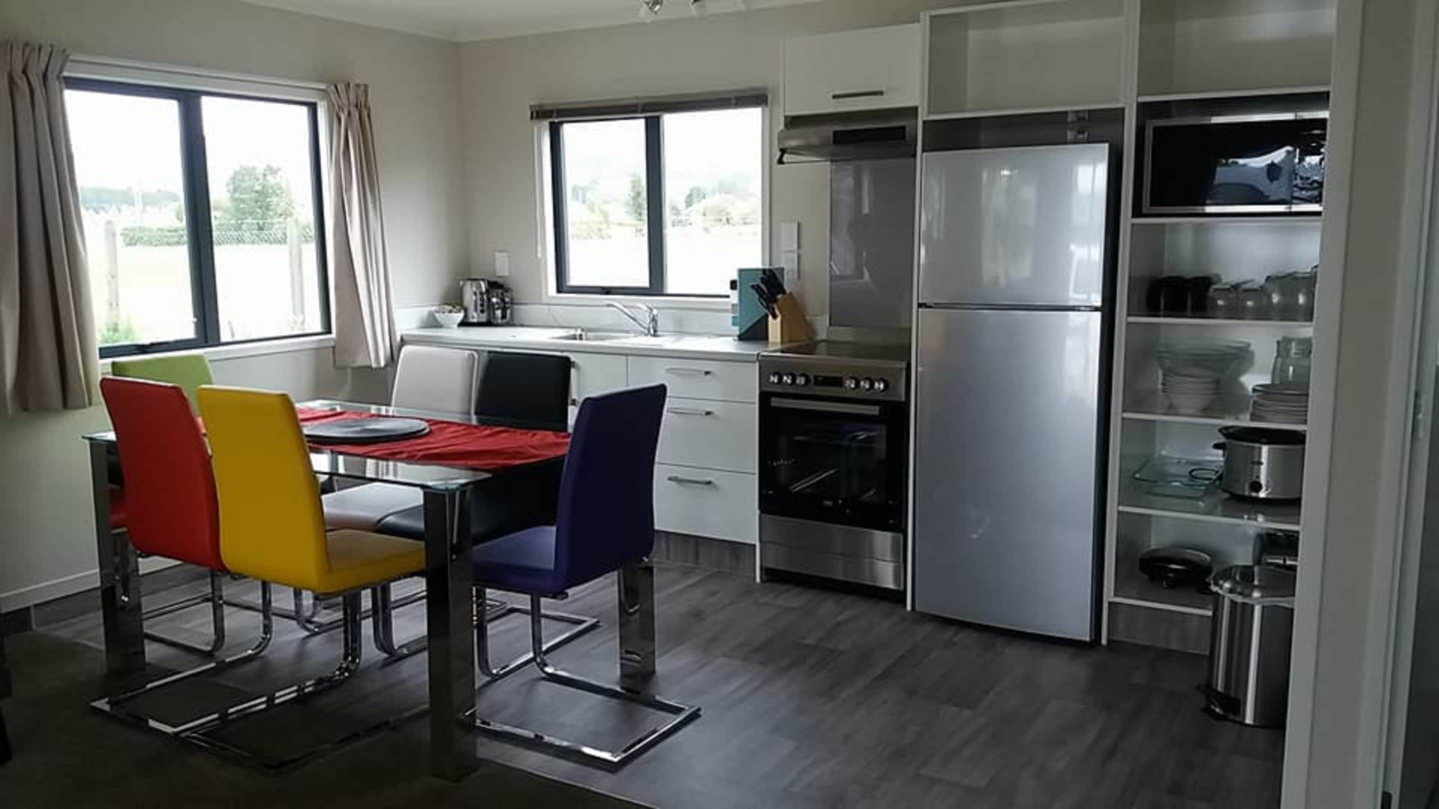 A modern kitchen with a dining area, stainless steel appliances, and a view of the outdoors.