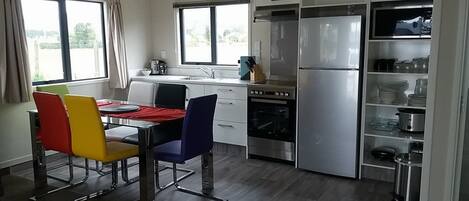 A modern kitchen with a dining area, stainless steel appliances, and a view of the outdoors.