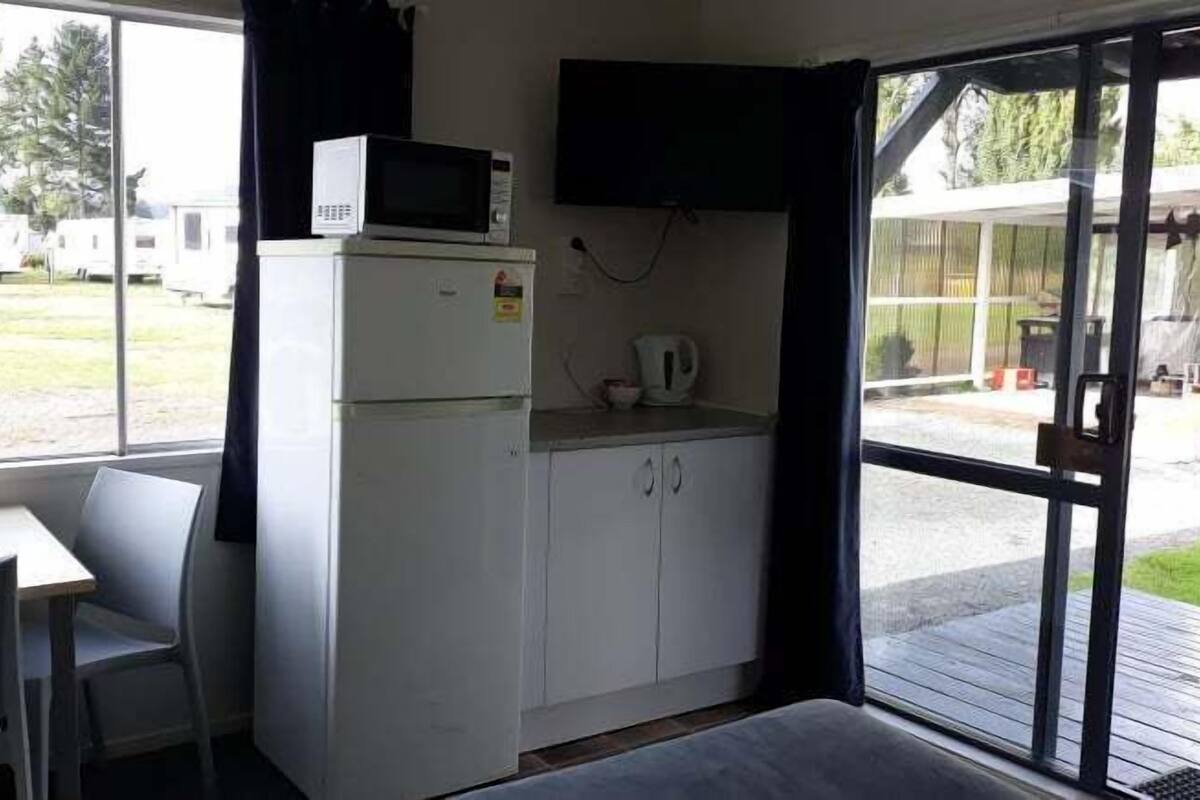A compact kitchenette with a microwave, a small refrigerator, and a coffee maker. There is a window providing a view of the outside.