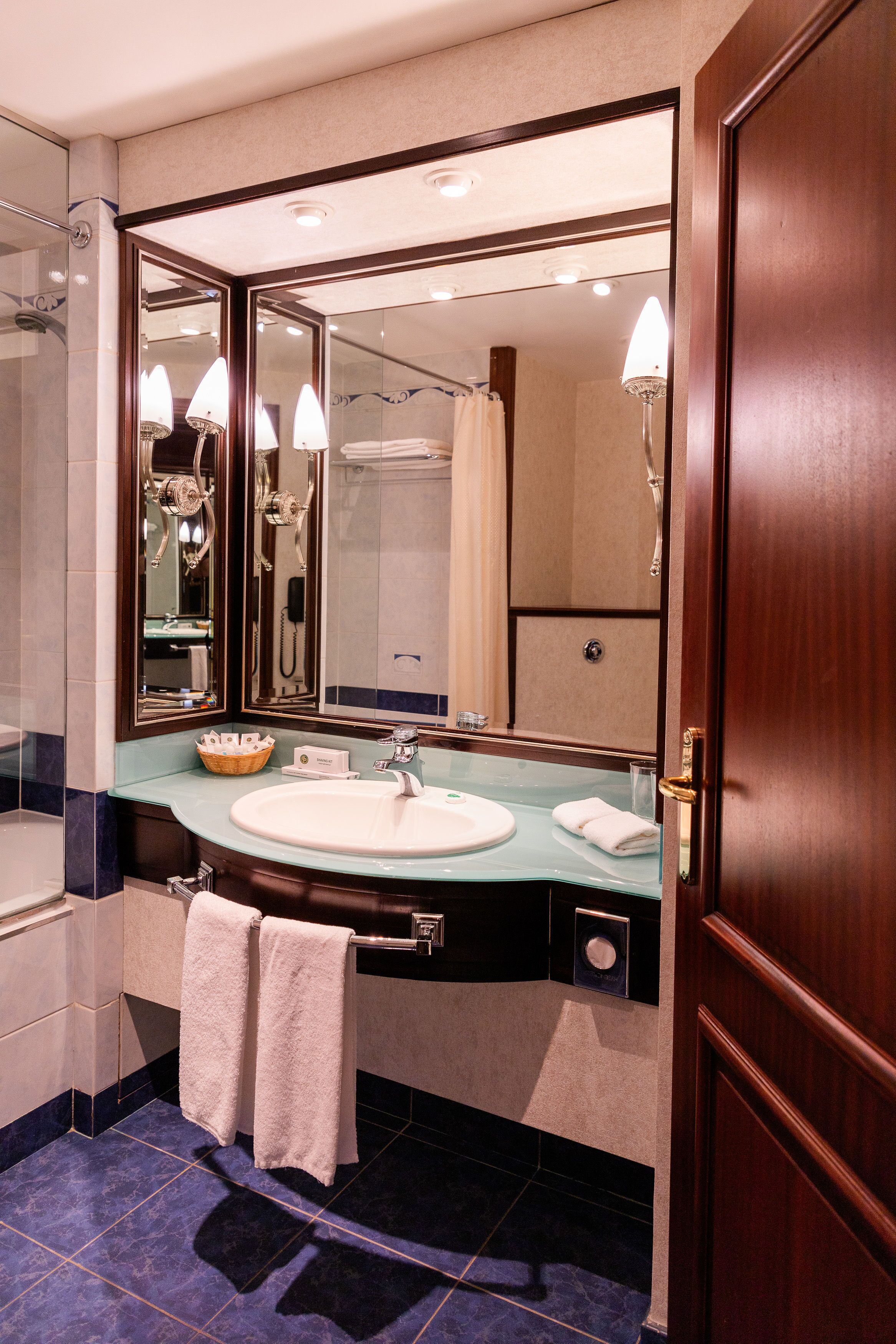 A modern bathroom with a large mirror, a sink, and a shower area.