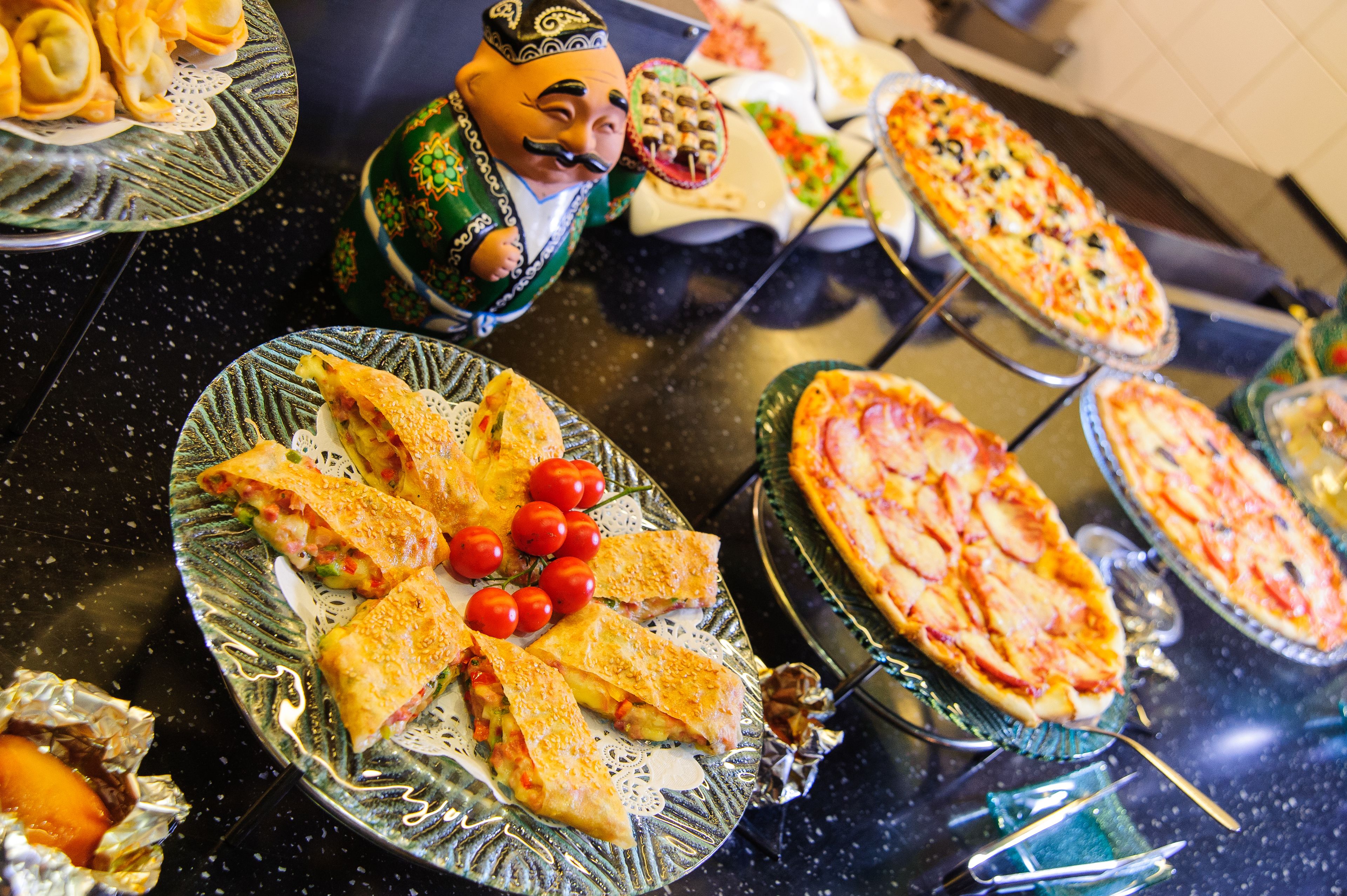 Un bufé con diversos platos, incluyendo sándwiches, pizzas y una figura decorativa.