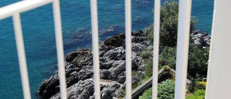 Vista costera con terreno rocoso y un mar azul y transparente.