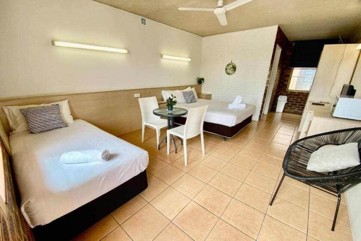 A hotel room with a bed, a small table with chairs, a desk, and a chair.