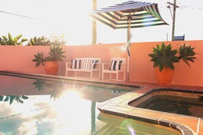 A swimming pool with two lounge chairs and a striped umbrella.