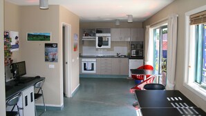 A compact kitchen with a dining area, a computer desk, and a view through the window. - Astray Motel (Rotorua)