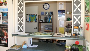 A small, well-organized office space with a desk, a clock, and various informational posters and books. - Astray Motel (Rotorua)